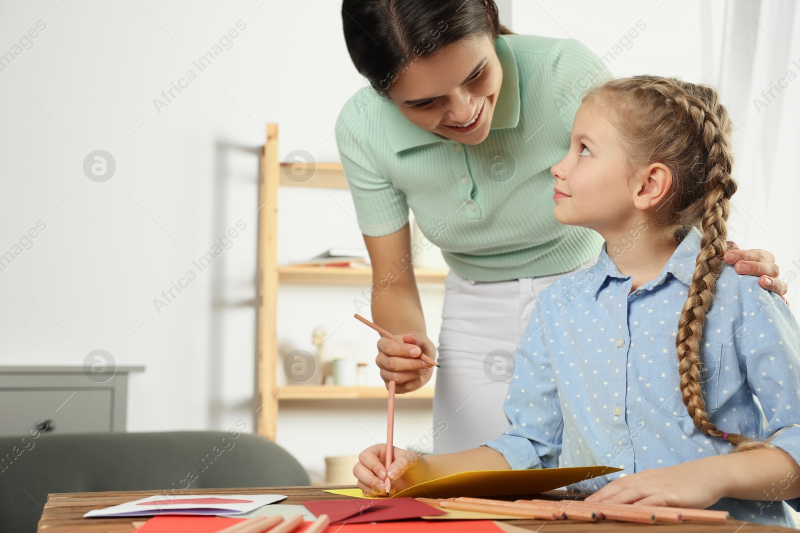 Photo of Cute little girl with her mother making beautiful greeting card at home