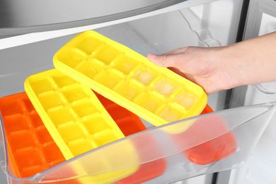 Photo of Woman taking tray with ice cubes from fridge, closeup