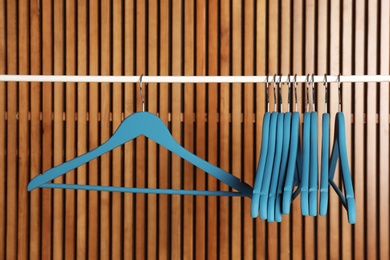 Photo of Empty hangers on rail against wooden background