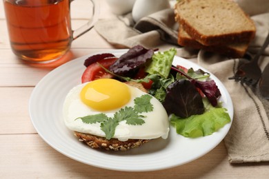 Delicious breakfast with fried egg and salad served on light wooden table, closeup