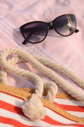 Photo of Beautiful sunglasses and bag on pink blanket