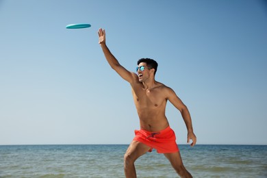 Happy man catching flying disk at beach on sunny day