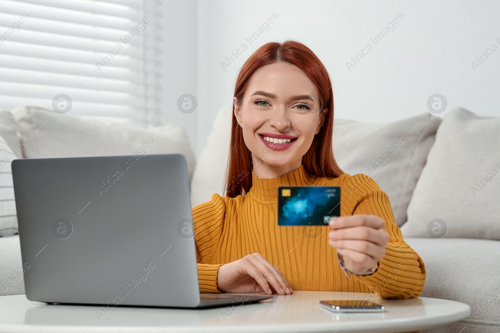 Photo of Happy woman with credit card near laptop at home. Online shopping