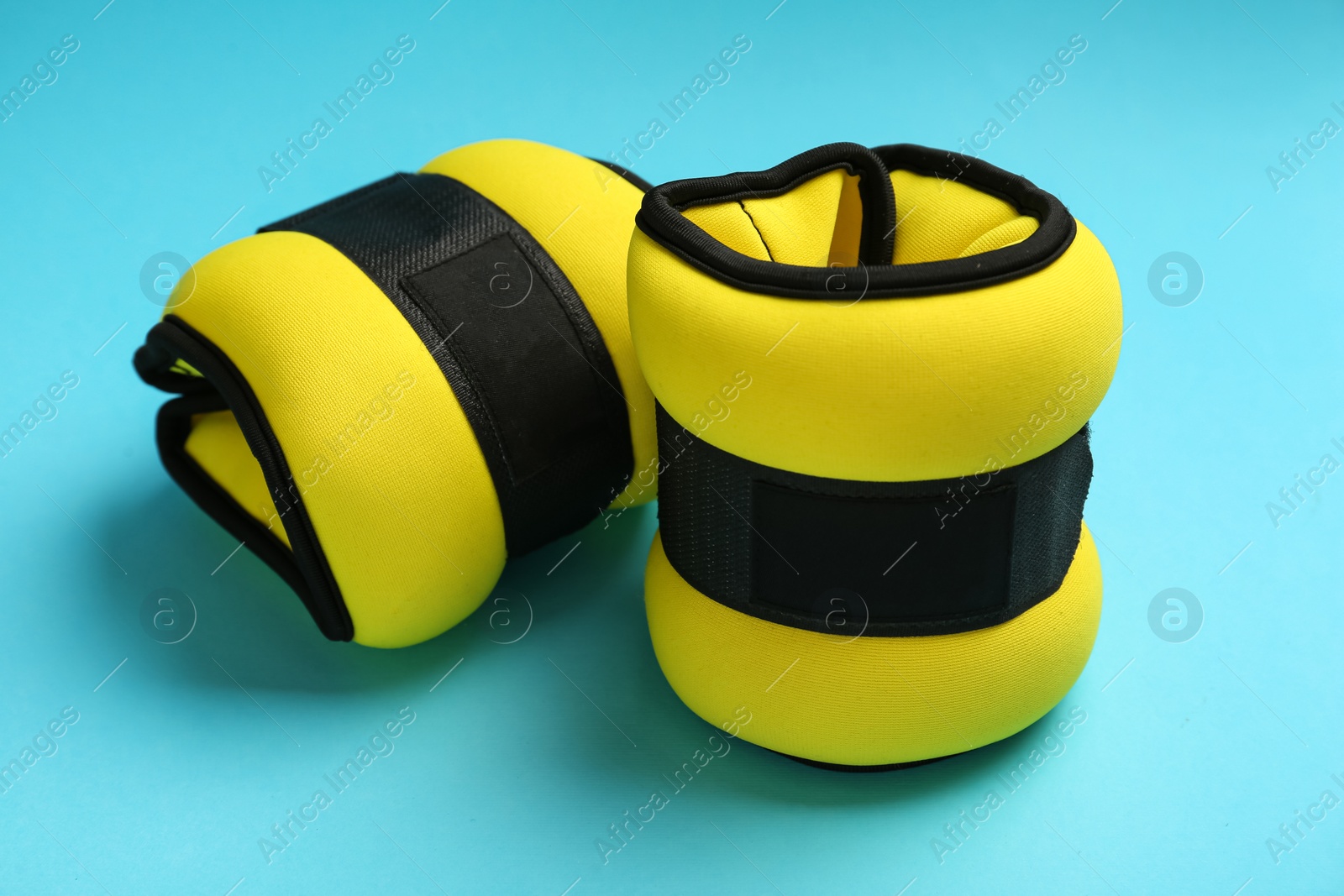 Photo of Stylish yellow weighting agents on light blue background