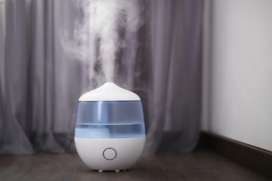 Photo of Modern air humidifier on floor at home