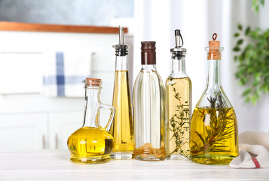 Photo of Different sorts of cooking oil in bottles on table indoors