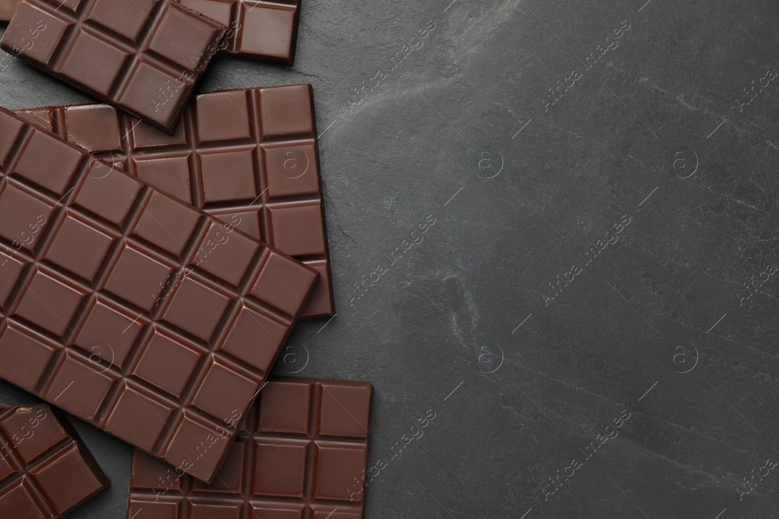 Photo of Pieces of tasty chocolate bars on grey table, flat lay. Space for text