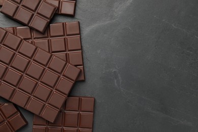 Photo of Pieces of tasty chocolate bars on grey table, flat lay. Space for text