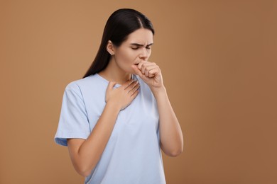 Photo of Woman coughing on brown background, space for text. Cold symptoms