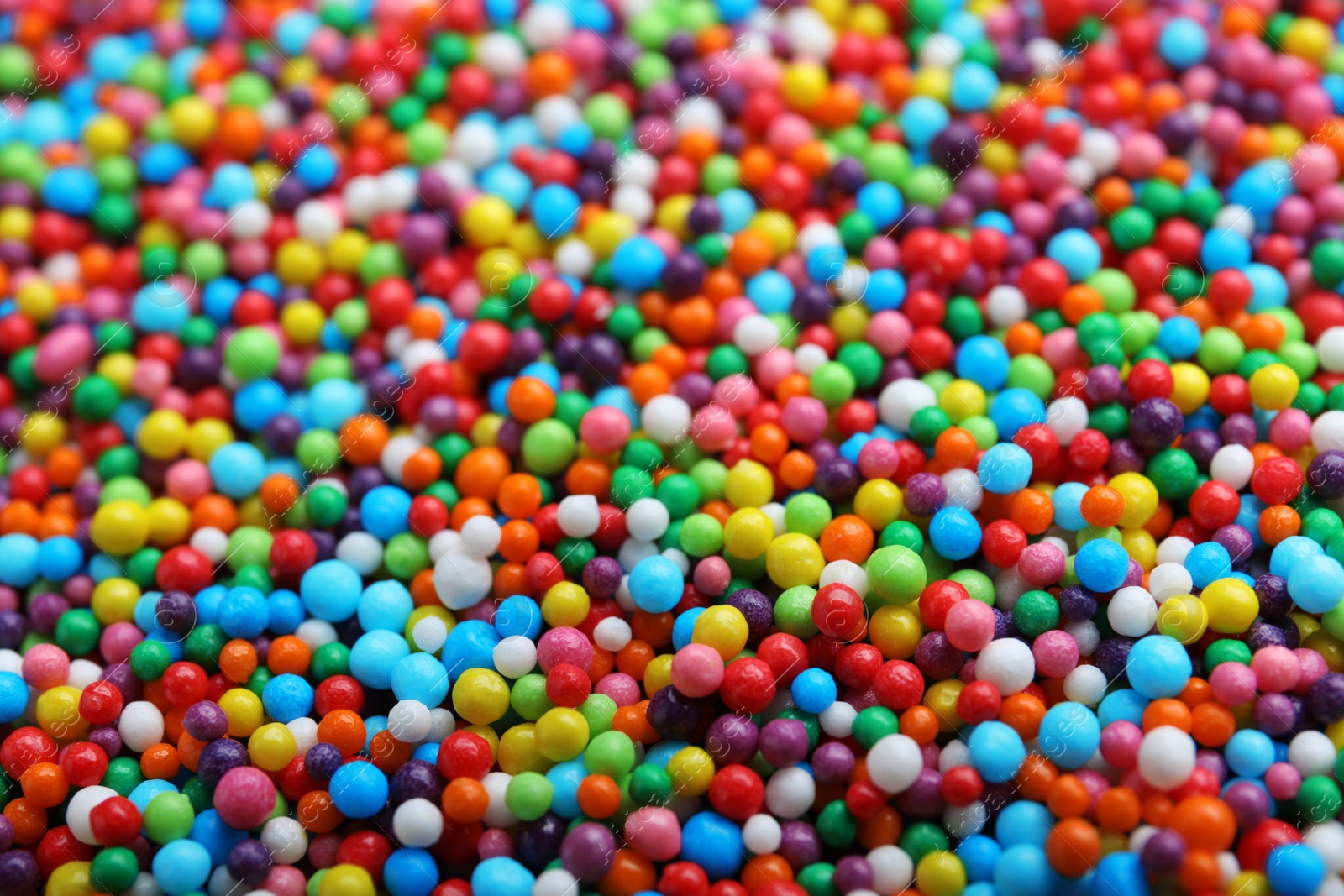 Photo of Bright colorful sprinkles as background, closeup. Confectionery decor