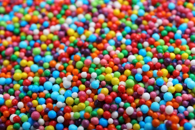 Bright colorful sprinkles as background, closeup. Confectionery decor