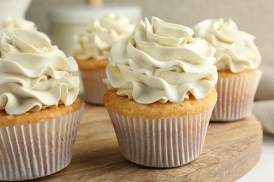 Tasty vanilla cupcakes with cream on table, closeup