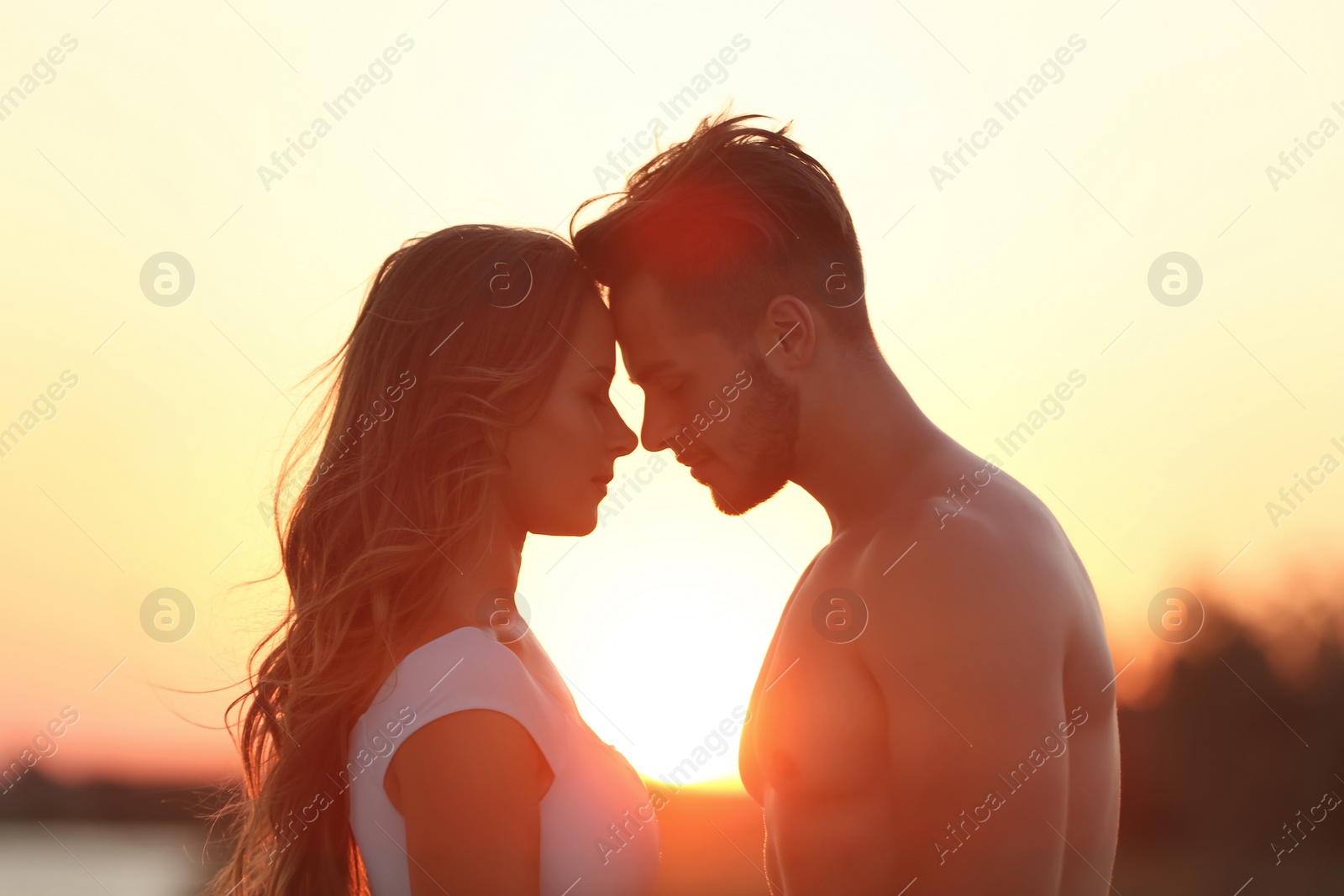 Photo of Happy young couple in beachwear outdoors at sunset