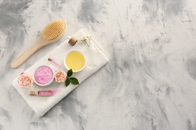 Photo of Flat lay composition with pink sea salt, flowers and different spa products on textured table. Space for text