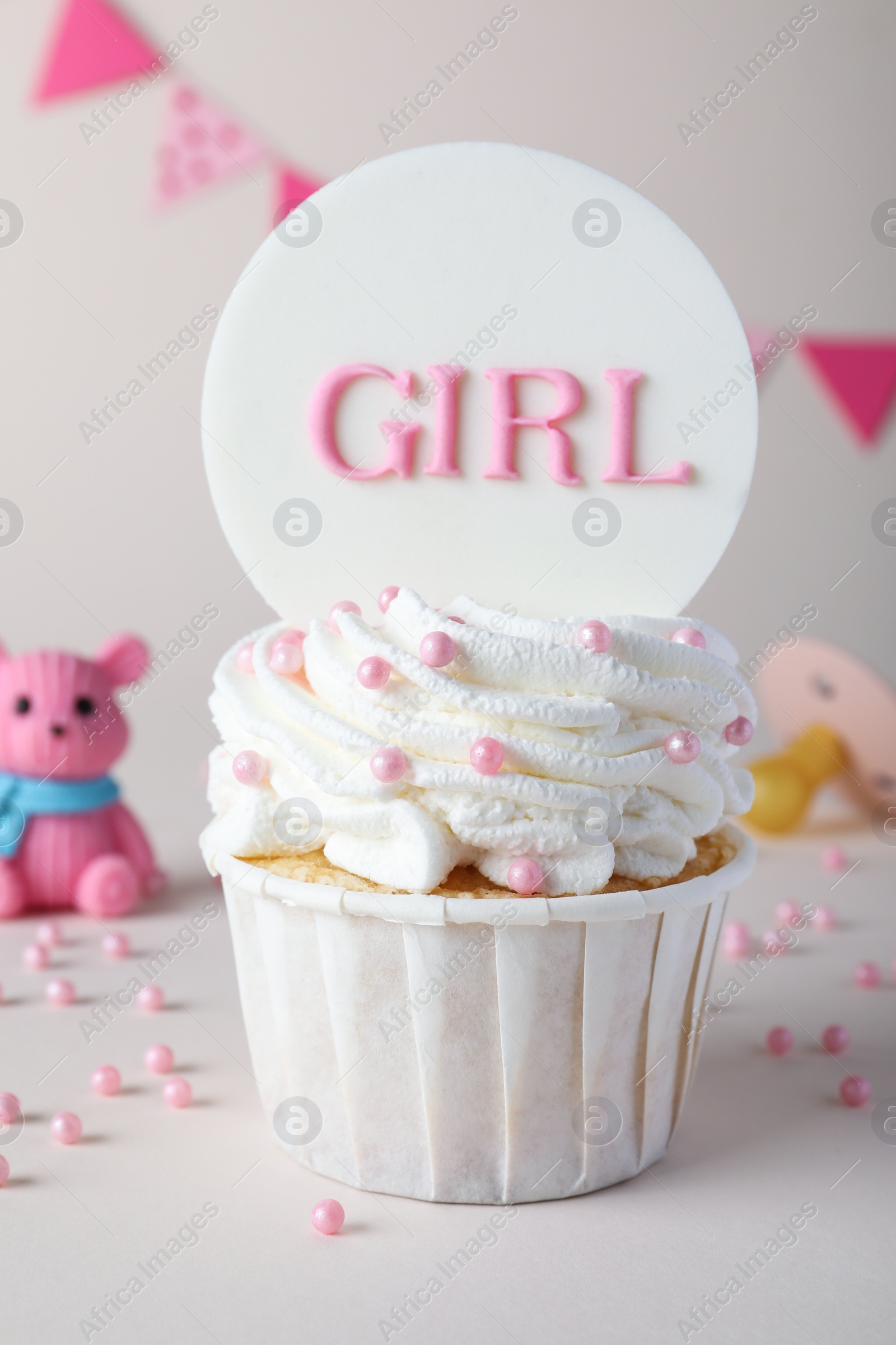 Photo of Beautifully decorated baby shower cupcake for girl with cream and topper on light background