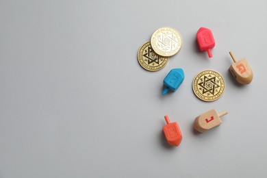 Photo of Dreidels with Jewish letters and coins on white background, flat lay with space for text. Traditional Hanukkah game