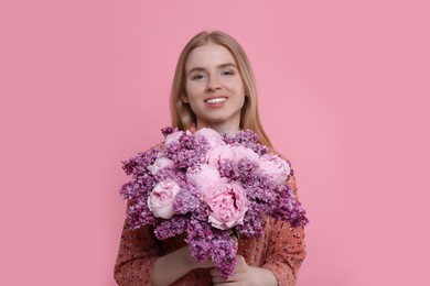 Beautiful woman with bouquet of spring flowers on pink background