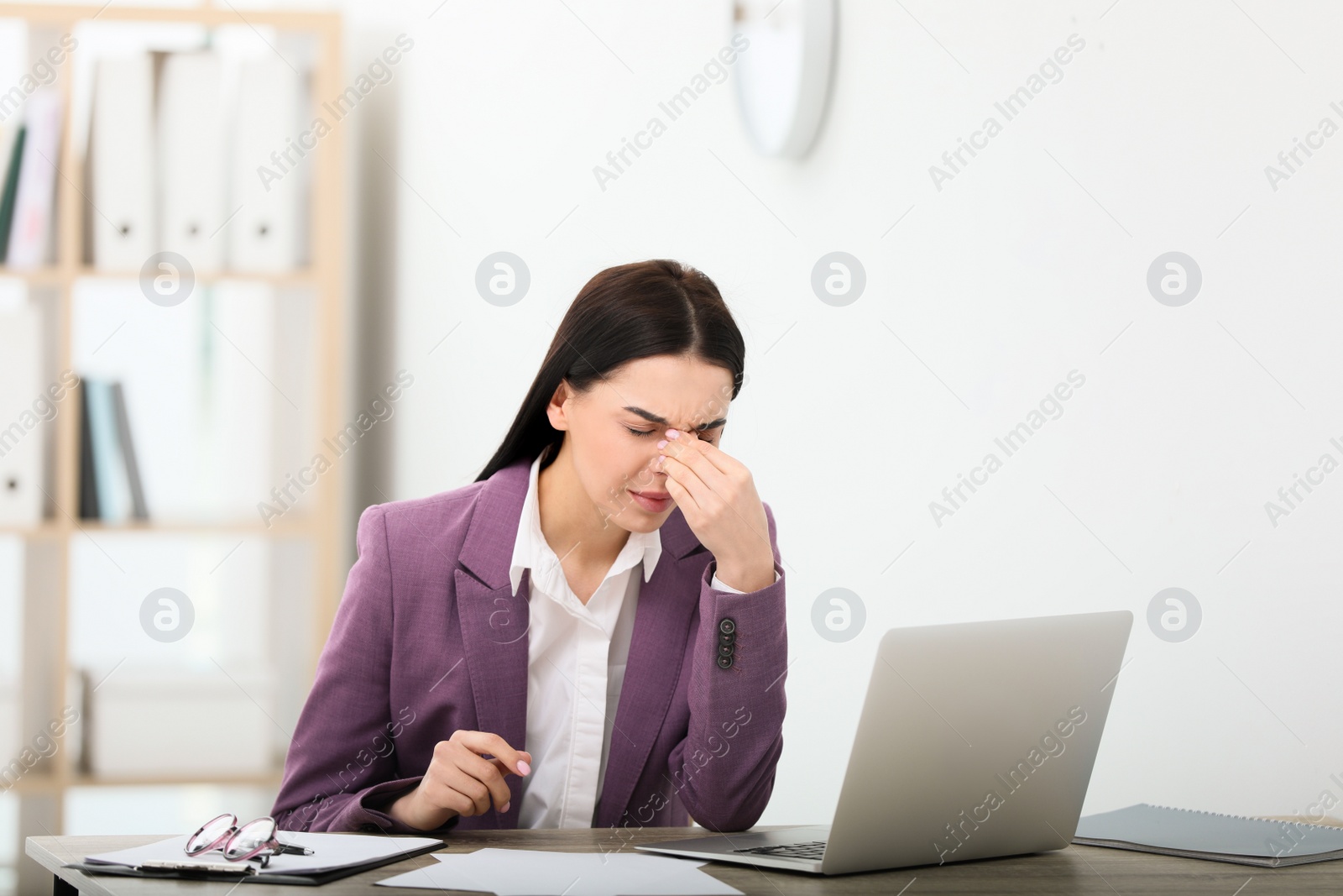 Photo of Woman suffering from migraine at workplace in office