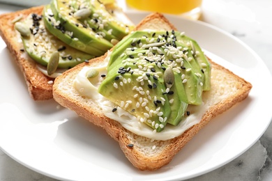 Photo of Toast bread with avocado and seeds on plate, closeup