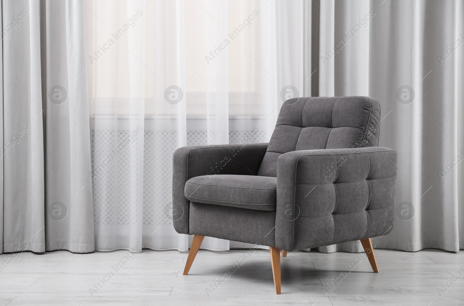 Photo of Comfortable armchair near window with stylish curtains in living room. Interior design