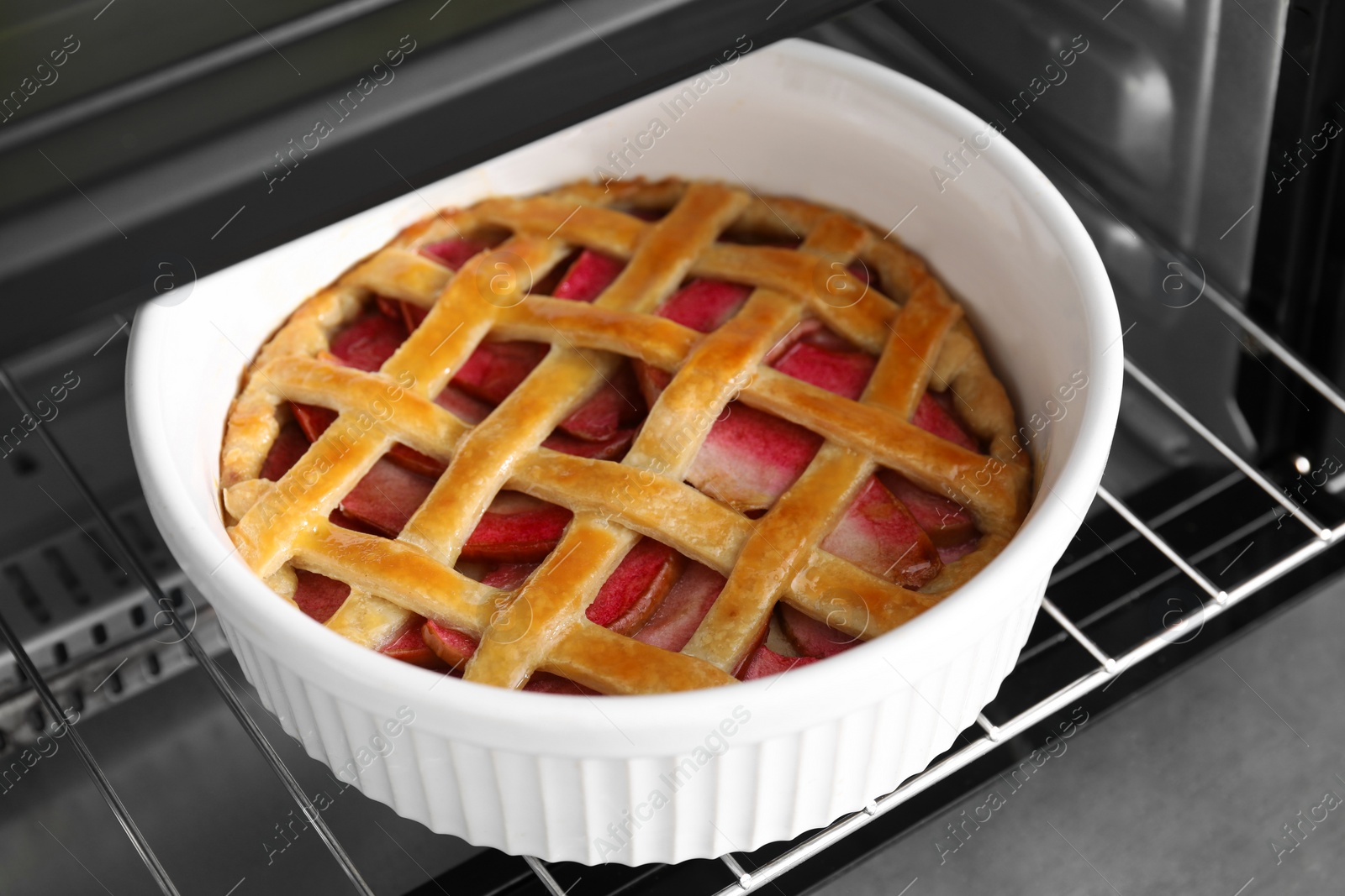 Photo of Baking dish with tasty apple pie in open oven, closeup