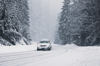 Photo of Snowy country road with modern car on winter day