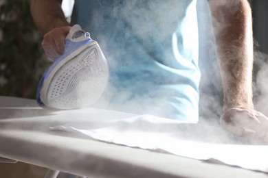 Photo of Man ironing clean shirt at home, closeup