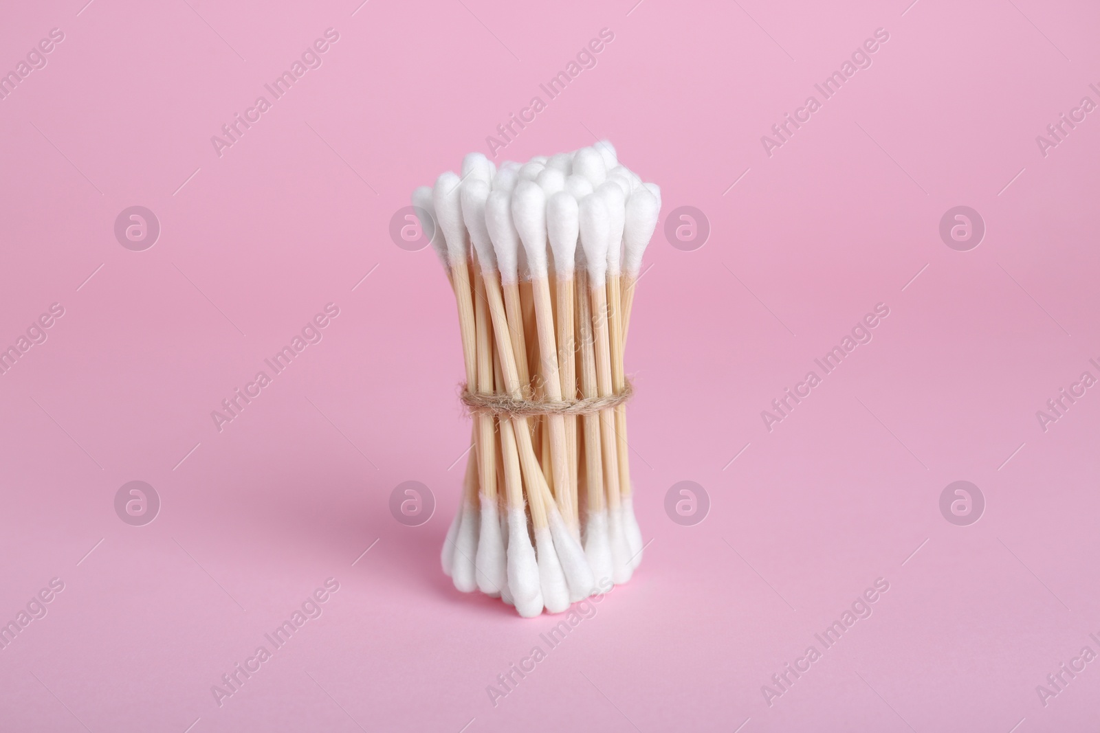 Photo of Bunch of wooden cotton buds on pink background