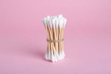 Photo of Bunch of wooden cotton buds on pink background