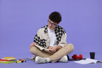 Portrait of student with notebook and stationery sitting on purple background