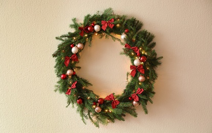 Photo of Beautiful Christmas wreath with festive decor on light wall