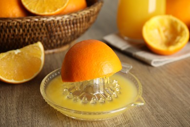 Squeezer and cut fresh oranges on wooden table, closeup