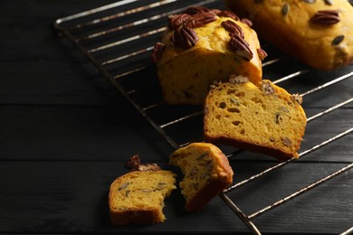 Photo of Delicious pumpkin bread with pecan nuts on black wooden table. Space for text