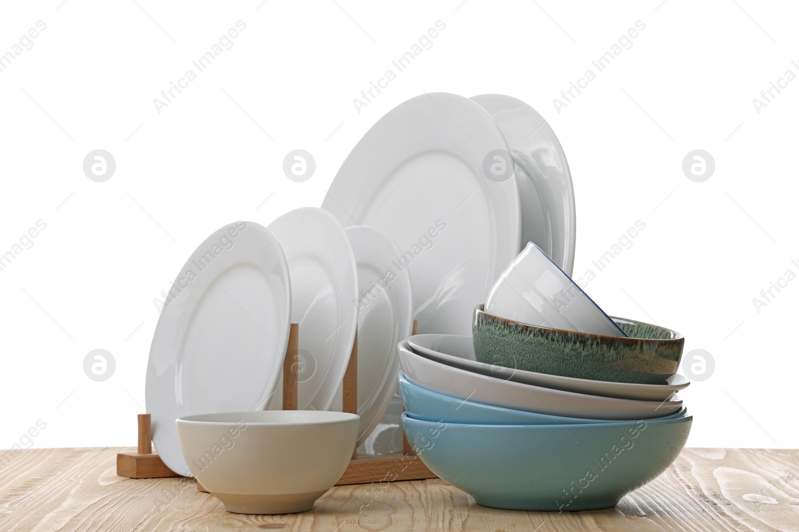 Photo of Set of clean color bowls and plates on wooden table against white background