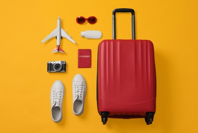 Flat lay composition with suitcase and travel accessories on yellow background. Summer vacation