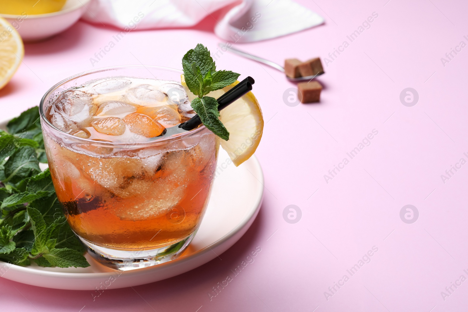 Photo of Delicious iced tea with lemon and mint on pink background, closeup. Space for text