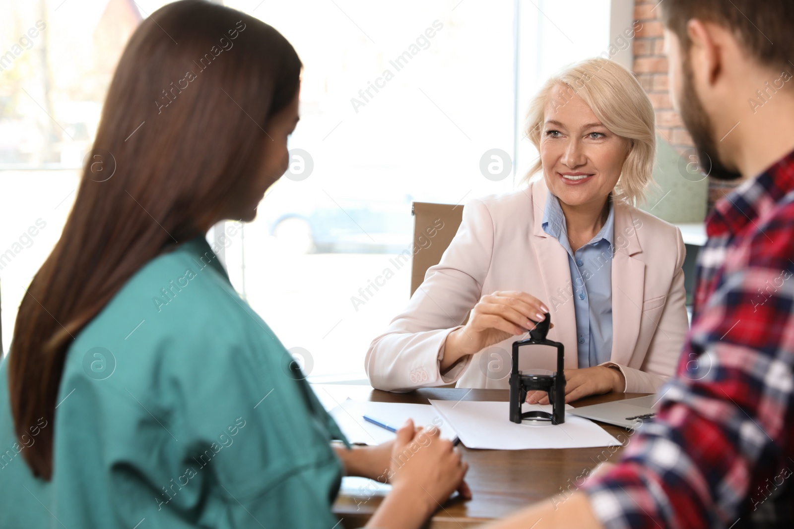 Photo of Female notary working with young couple in office