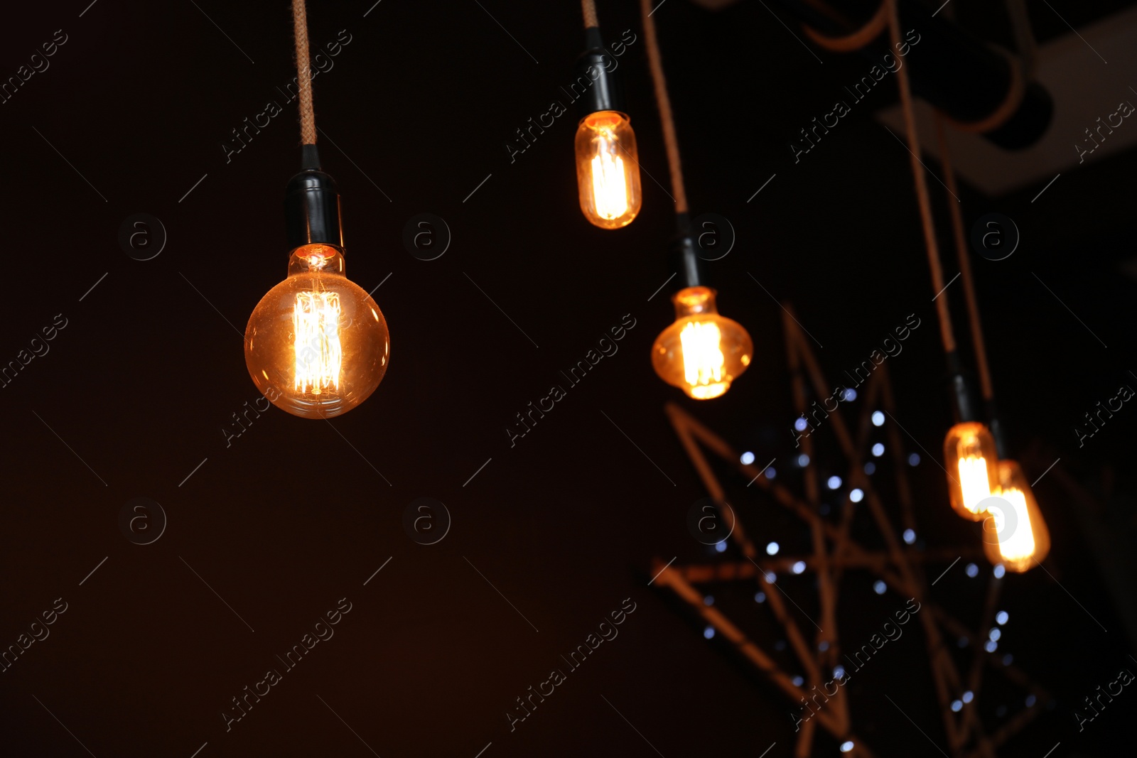 Photo of Glowing lamp bulbs in dark room. Interior element