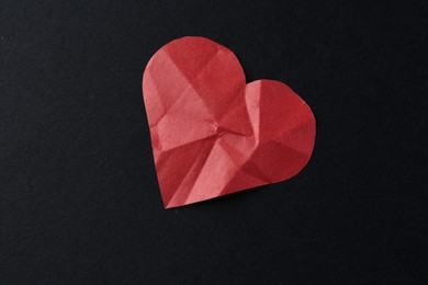 Photo of Red crumpled paper heart on black background, top view. Breakup concept