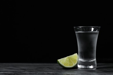Photo of Shot of vodka with lime slice on grey table. Space for text