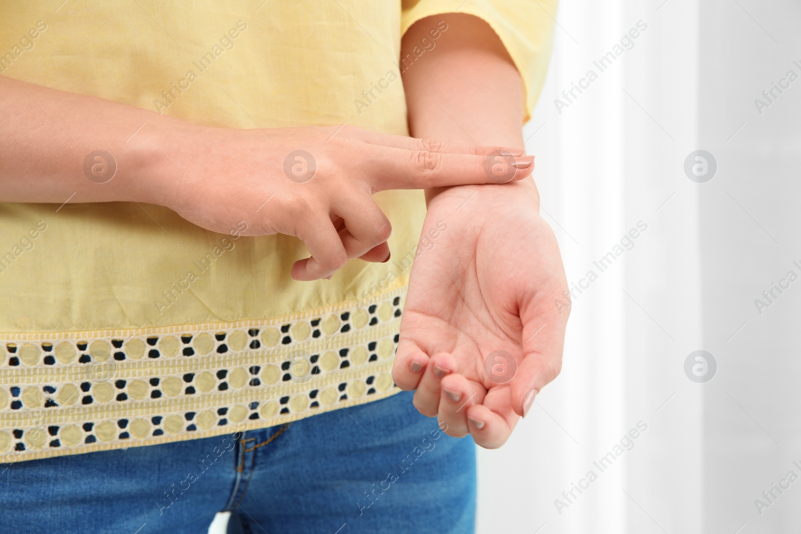 Photo of Young woman checking pulse on light background