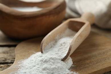 Baking powder in scoop on wooden table, closeup