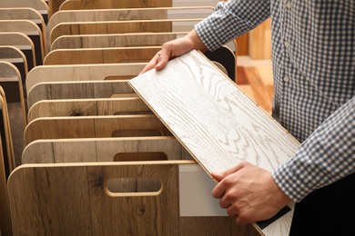 Man with sample of light wooden flooring in shop, closeup