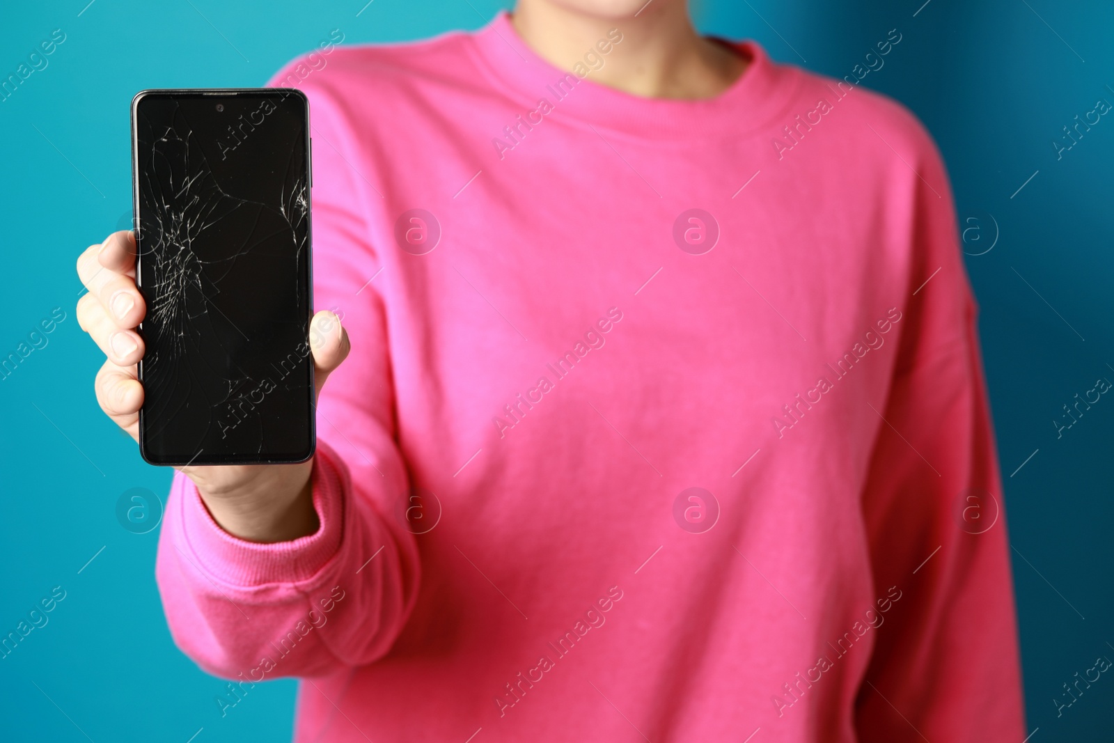 Photo of Woman showing damaged smartphone on light blue background, closeup. Device repairing