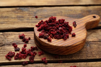 Photo of Board and dried red currant berries on wooden table