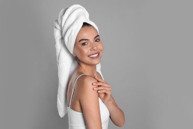 Photo of Beautiful young woman with towel on head against grey background