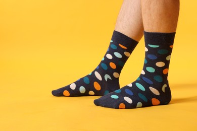 Photo of Man in stylish colorful socks on yellow background, closeup. Space for text