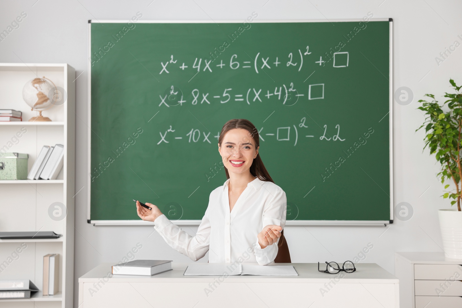 Photo of Young math’s teacher giving lesson at table in classroom