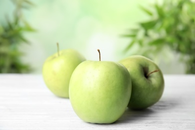 Photo of Fresh ripe green apples on white wooden table against blurred background, closeup view. Space for text