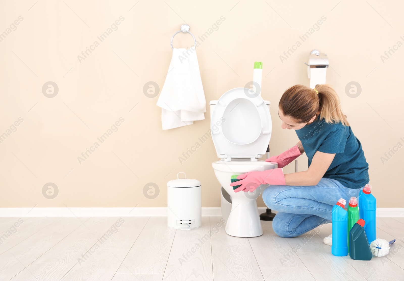 Photo of Woman cleaning toilet bowl in bathroom